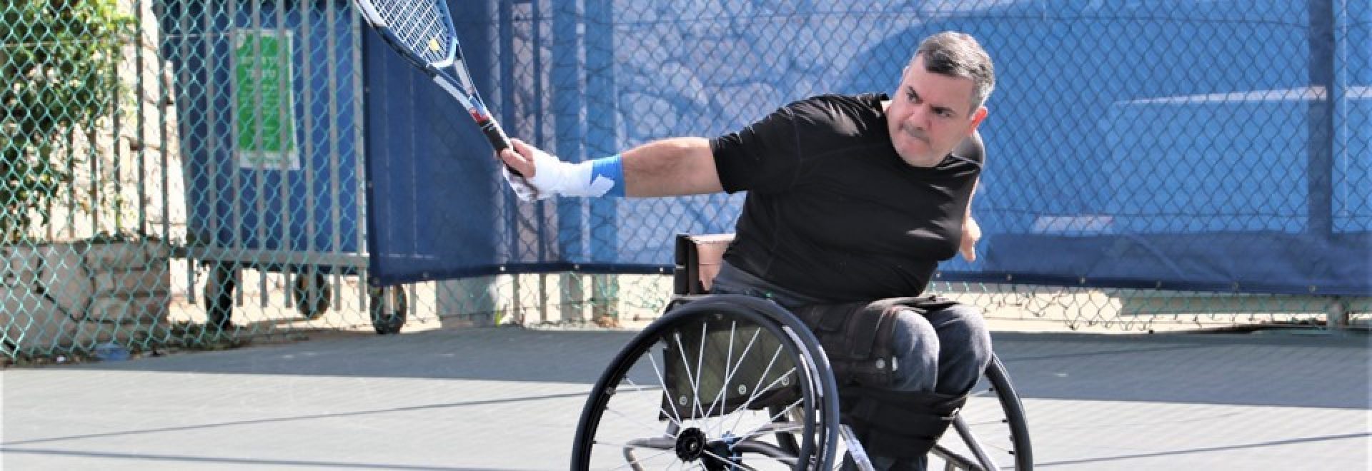 ספורטאי על כיסא גלגלים אוחז מחבט טניס