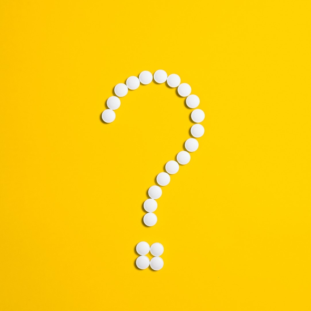 כדורי תרופות לבנים שיוצרים סימן שאלה עם רקע צהוב